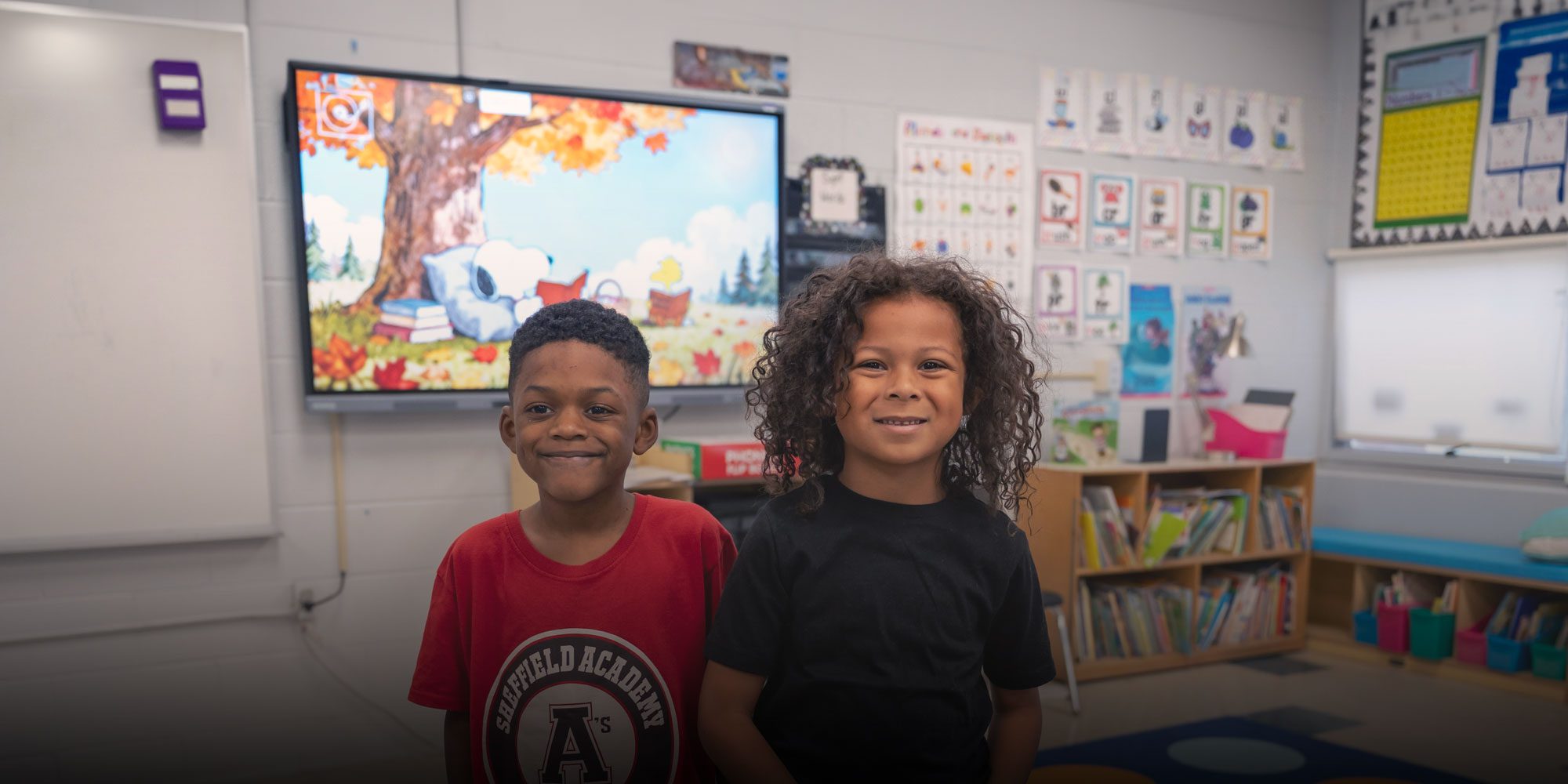 Two smiling students in a classroom.